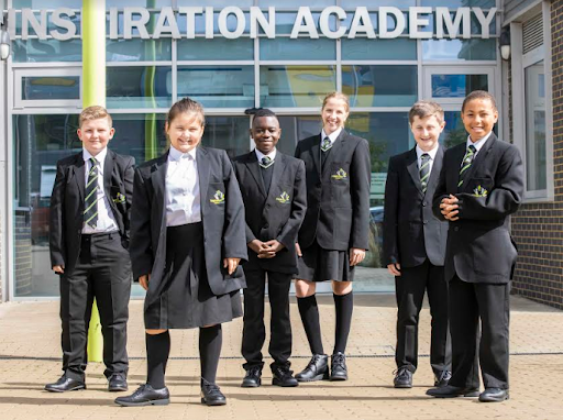 Small group of Inspiration Academy students are shown posing for a photo outside the Inspiration Academy building.