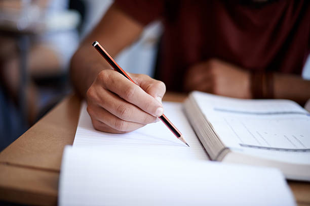 Closeup picture of someone writing in a notepad with a pencil