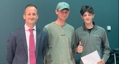 Three people posing for a photo on results day, with one student holding their results