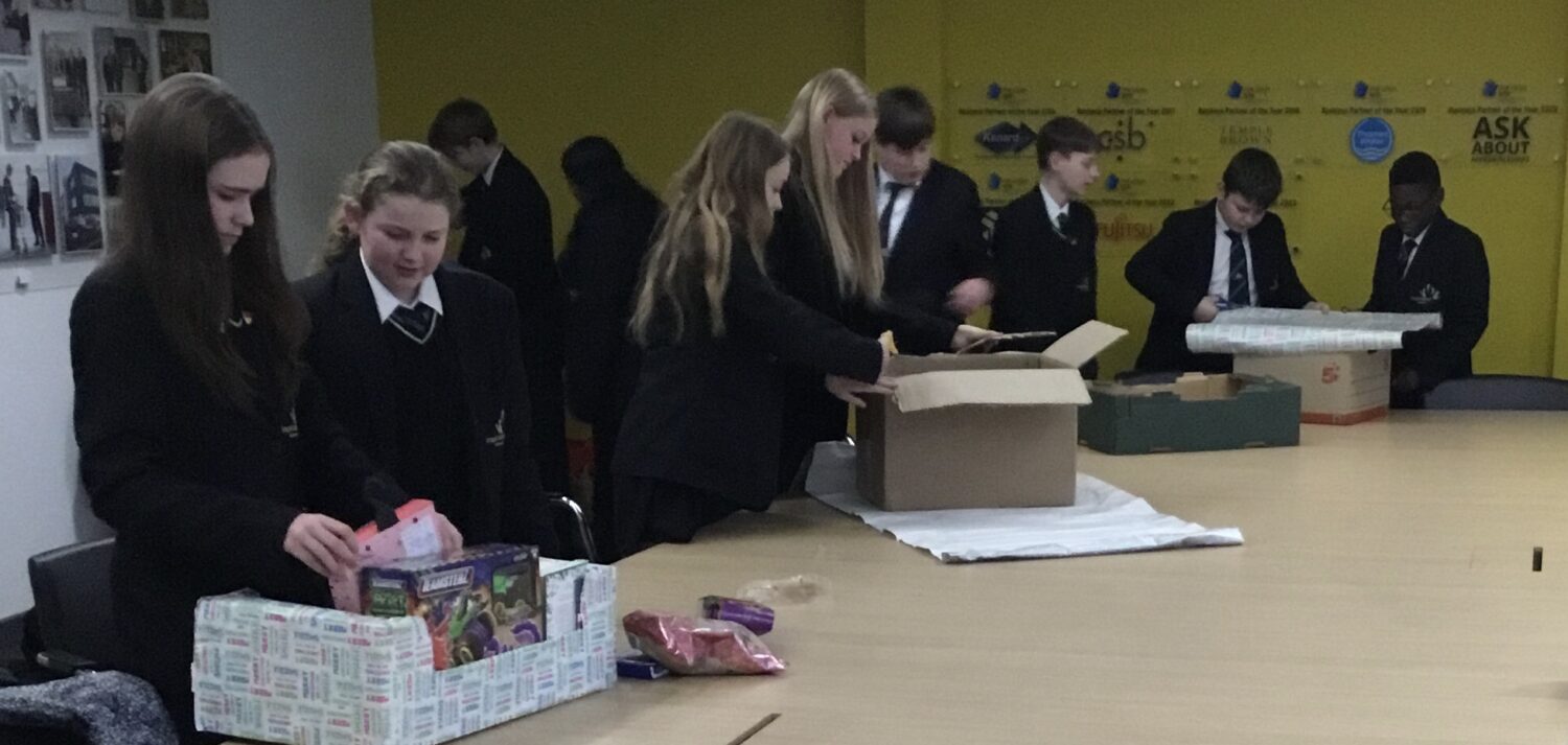 Students stood around a table looking into cardboard boxes full of items