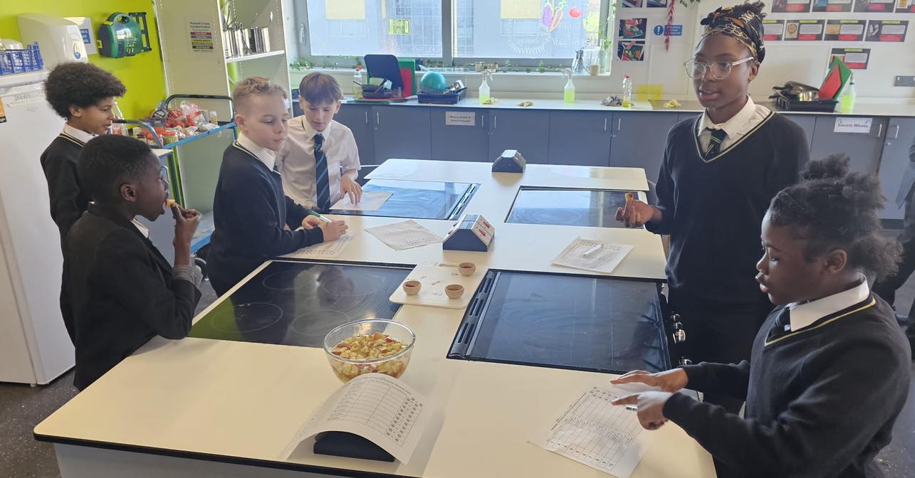 Students around a table reading recipes