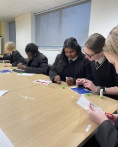 Students at a desk cutting and gluing pieces of paper